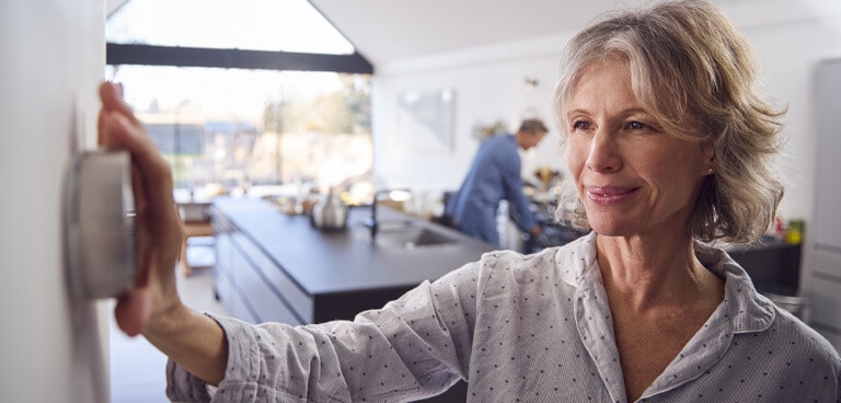 woman adjusts a smart home thermostat