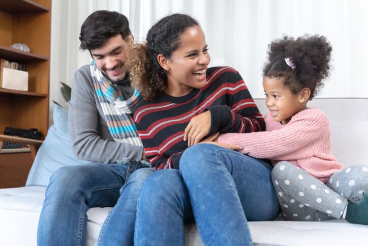 Happy family on a couch, laughing and hugging each other.