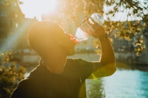 man drinks bottled water on a hot day