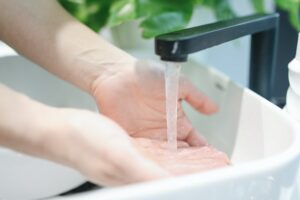 woman washes hands under a flowing faucet