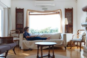 woman relaxes on couch under air conditioning unit