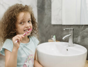 child brushes teeth with faucet off to conserve water