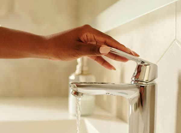 person adjusts faucet