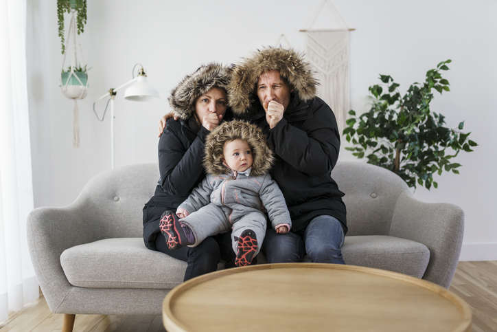 Couple and baby in warm clothing on sofa