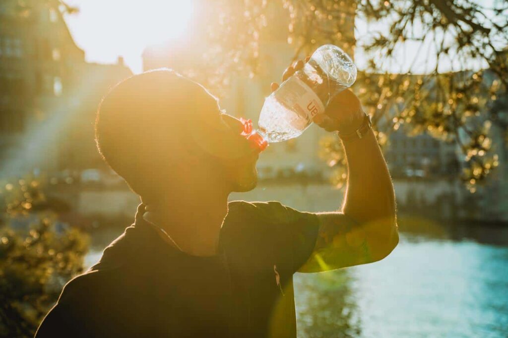 man drinks bottled water on a hot day
